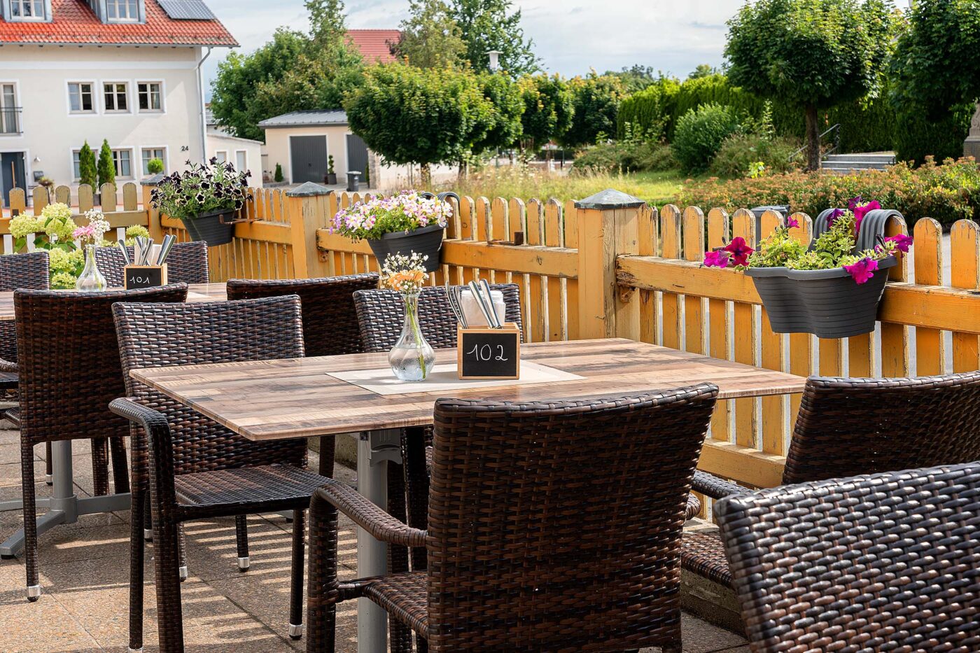 Terrassenmöbel klappbares Tischgestell aus Aluminium sowie stapelbare Rattanstühle auf einer Restaurantterrasse